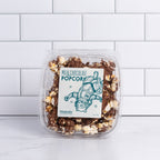 Small clear tub of Winfield's Milk Chocolate Popcorn