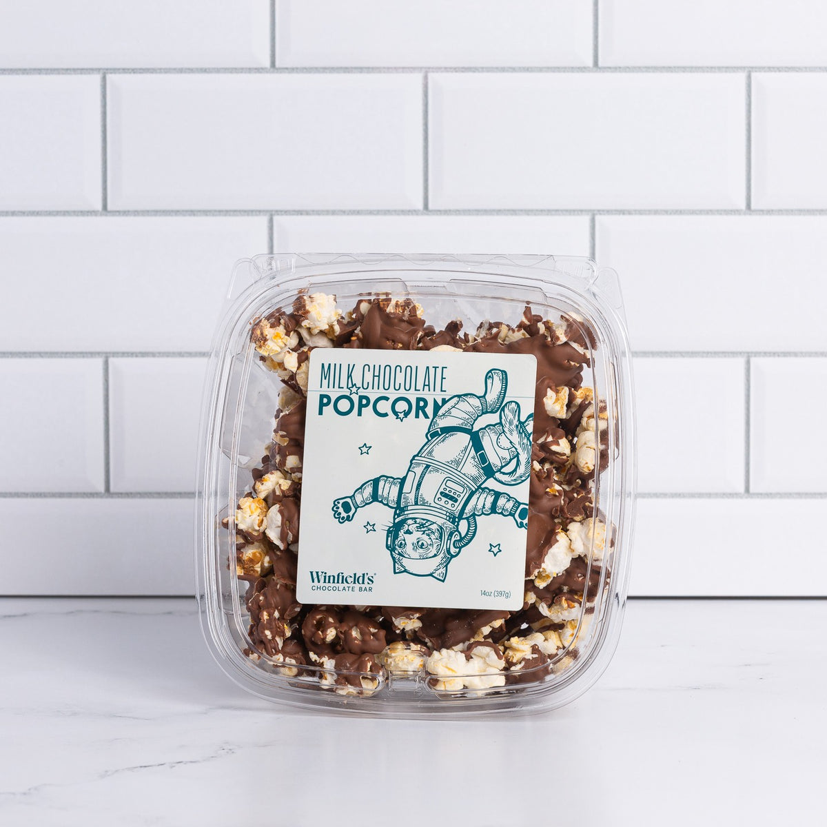 Small clear tub of Winfield's Milk Chocolate Popcorn