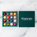 Winfield's Signature Truffle Collection 16-piece box open from above, teal tray beside the dark green lid