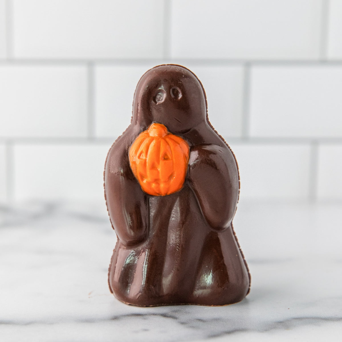 Winfield's dark chocolate Ghost holding an orange jack-o'-lantern pumpkin