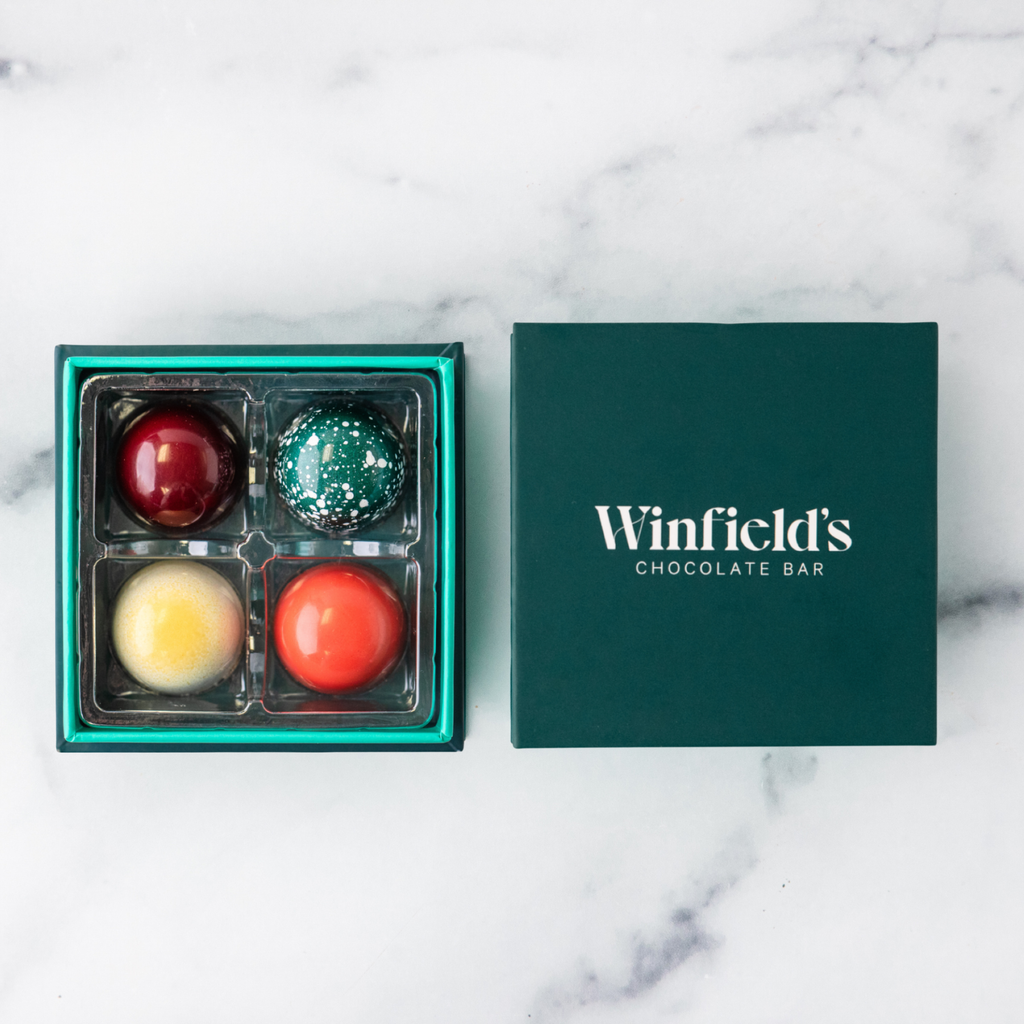 Winfield's Signature Truffle Collection 4-piece box open on marble, teal tray beside the dark green lid