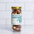 Tall glass jar with a gold lid filled with Winfield's Milk Chocolate Popcorn