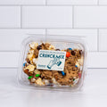 Clear tub of Winfield's Crunch Mix with chocolate-coated pretzels, popcorn and candy-shell pieces