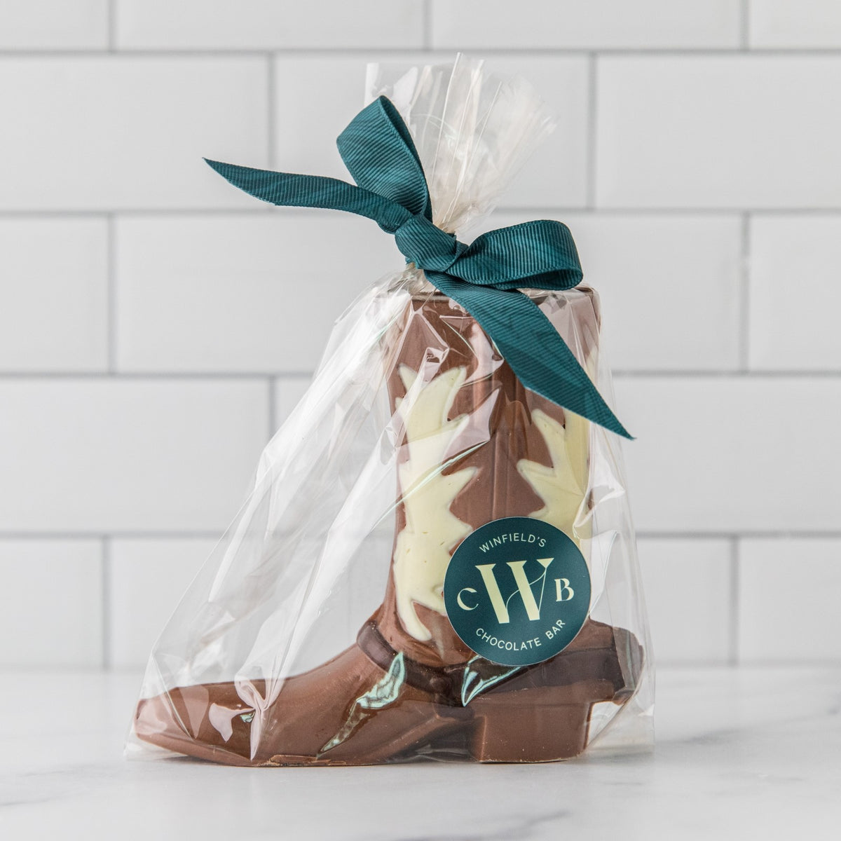 Winfield's molded chocolate cowboy boot bagged in cellophane with a teal ribbon and the Winfield's seal