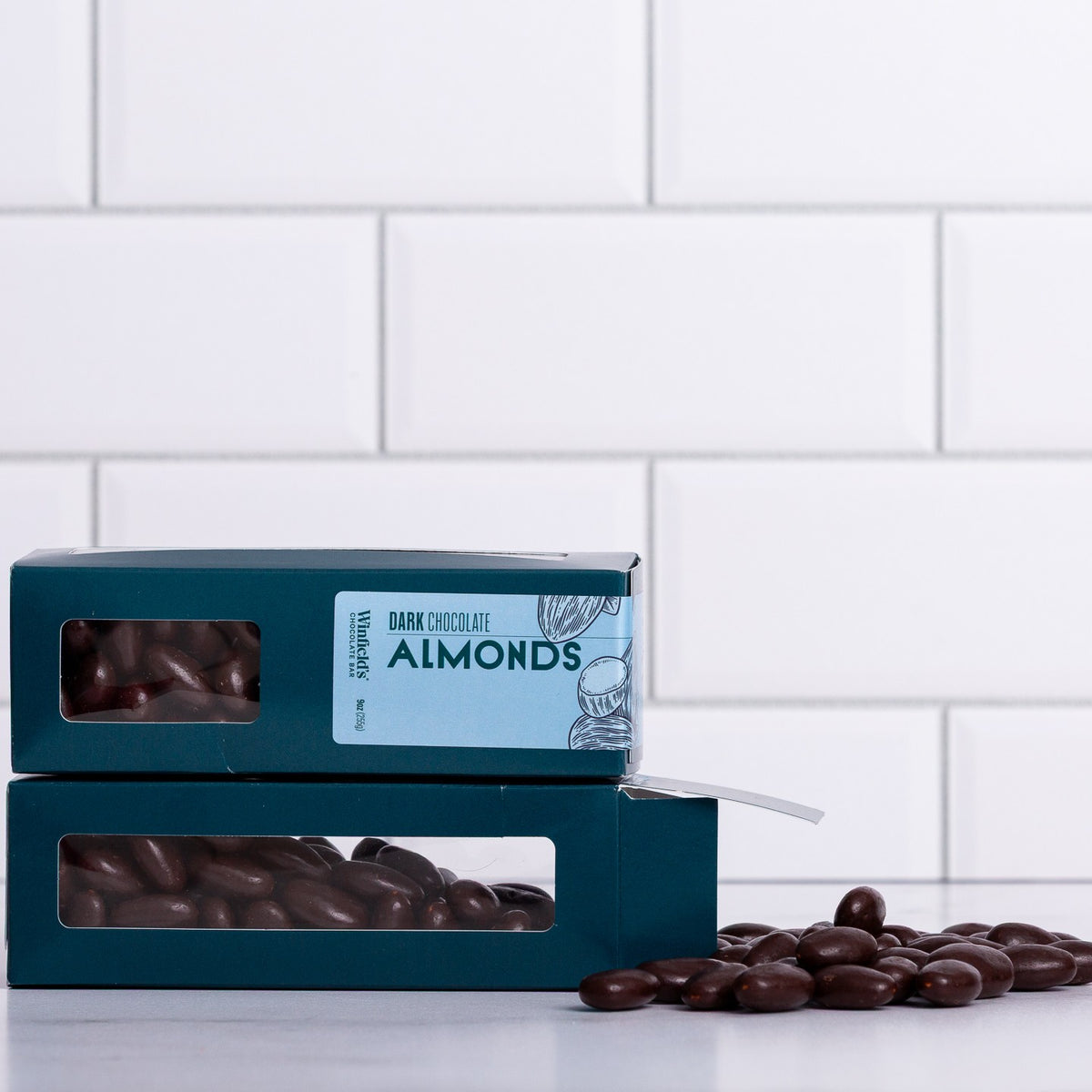 Winfield's Dark Chocolate Almonds in stacked teal window boxes with loose almonds alongside