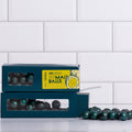 Winfield's Salted Dark Chocolate Malt Balls in stacked teal window boxes with loose malt balls alongside