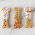 Three Winfield's large dog-bone biscuits finished with yogurt coating and rainbow sprinkles