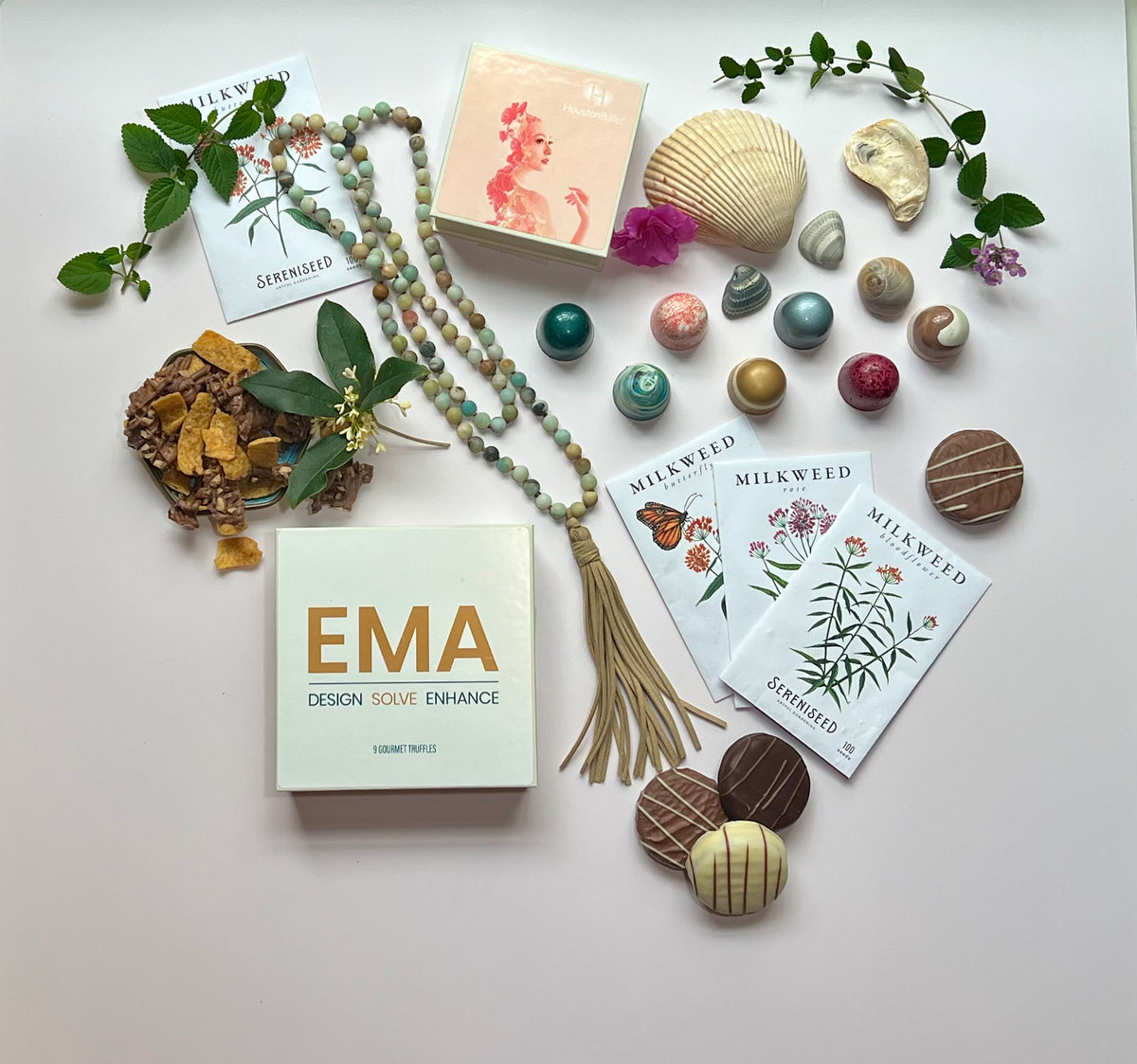 A custom EMA Design Solve Enhance gift box with wildflower-print Winfield's chocolate bars and assorted truffles arranged with beads, shells and greenery