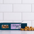 Winfield's Gold Chocolate Hazelnuts in a teal window box with loose gold-dusted hazelnuts alongside