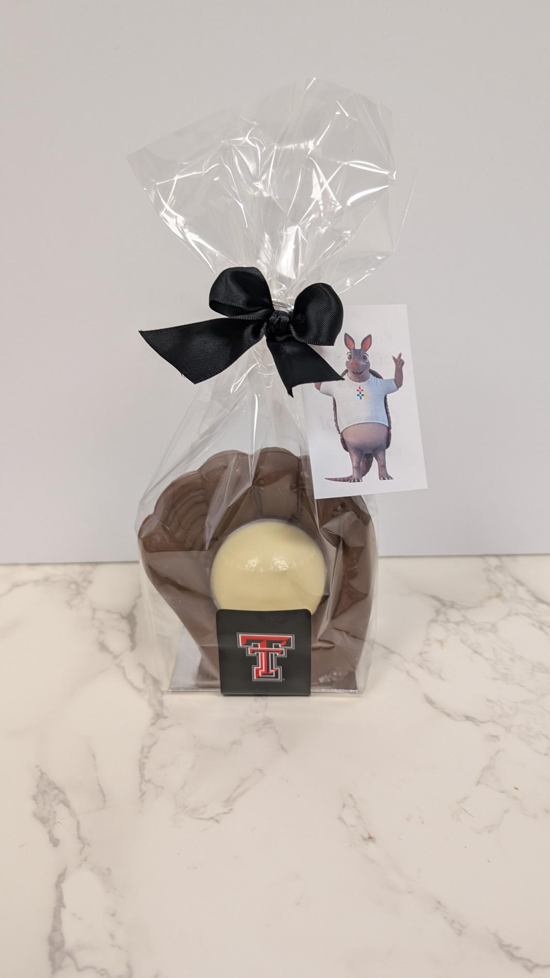 A molded chocolate figure sealed in a clear cellophane bag with a black bow and a gift tag