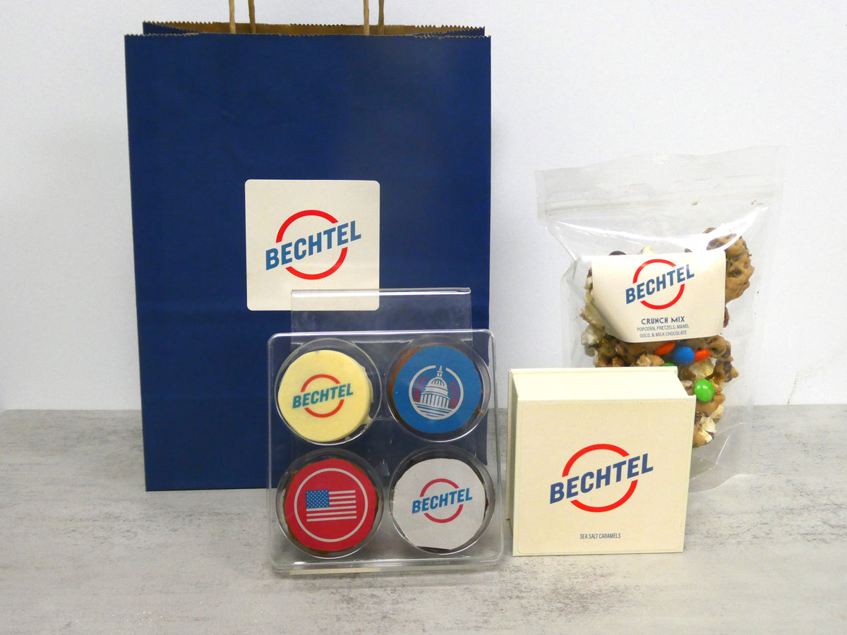 A Bechtel-branded navy gift bag with a printed box and logo chocolate coins in a clear window case