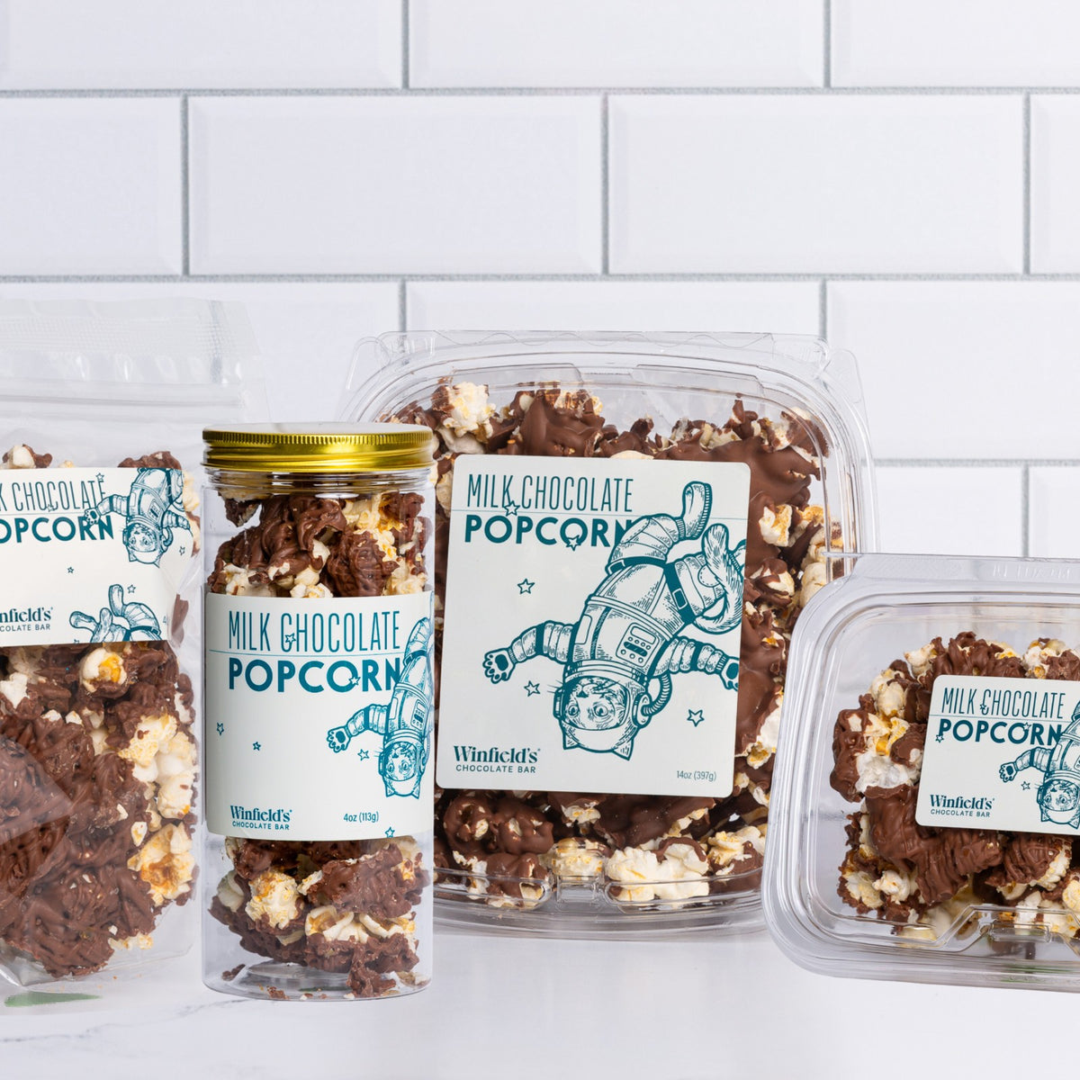 The Winfield's Milk Chocolate Popcorn range — glass jar, stand-up pouch and clear tubs — with the astronaut label