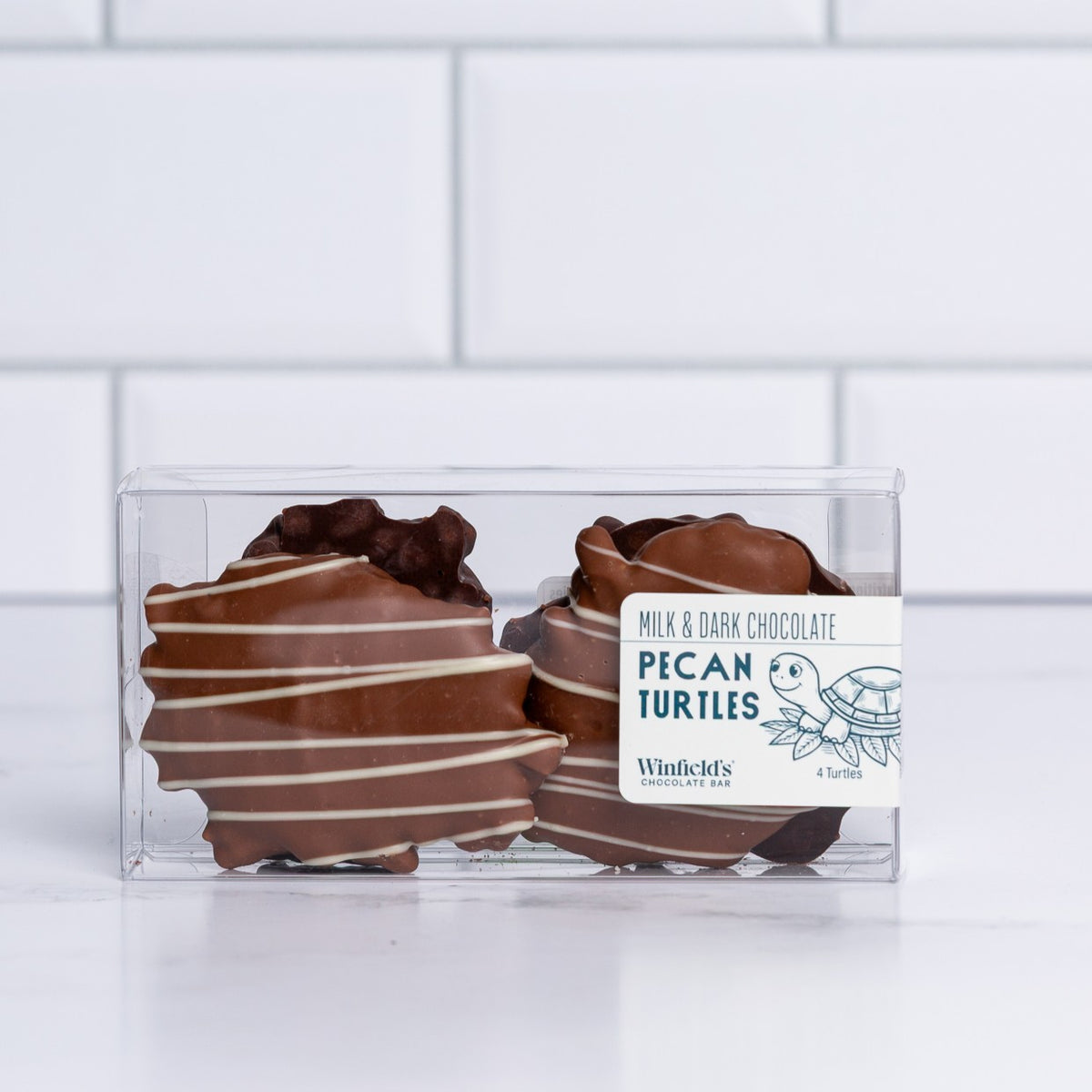 Winfield's Pecan Turtles in milk and dark chocolate, shown in a clear gift box