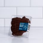 A single Winfield's dark chocolate pecan turtle in a clear gift box