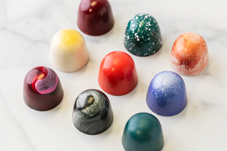 Nine hand-painted Winfield's signature truffles scattered across marble