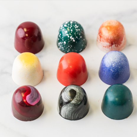 Nine Winfield's signature truffles in three rows, each hand-painted in a different colour, on marble