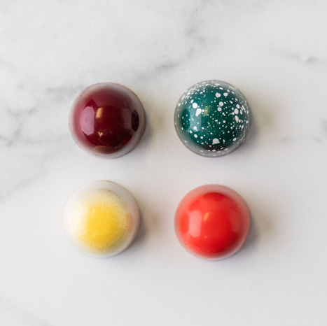 Four hand-painted Winfield's signature truffles arranged on a marble surface