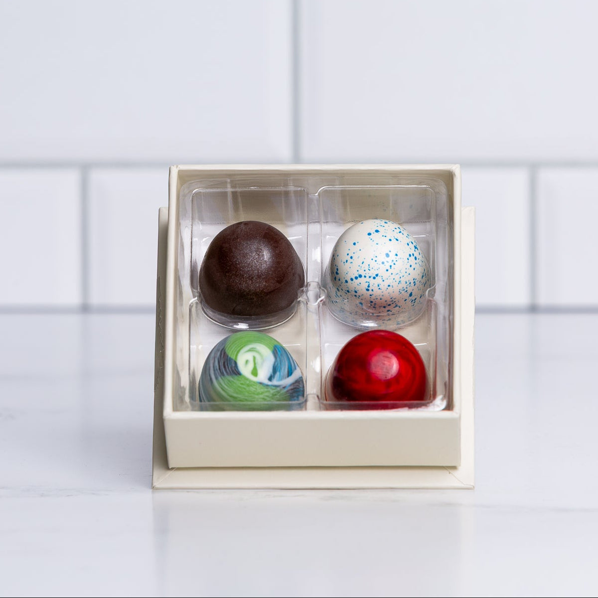 Four Winfield's Space City truffles in an open box, hand-painted with galaxy finishes