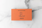 Closed orange Winfield's Texas-Made Caramels box with the cowboy-boot crest, on marble