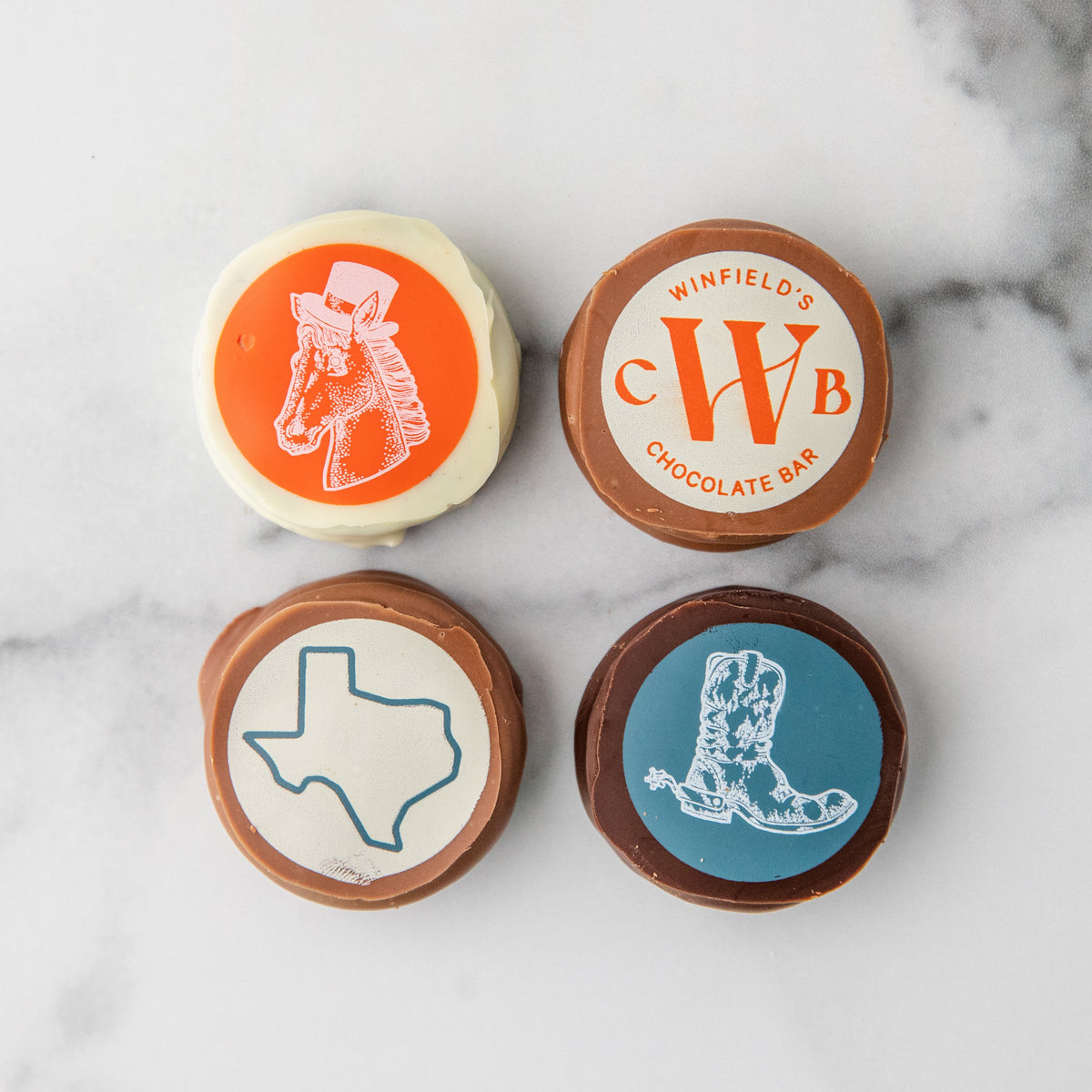 Four Winfield's Texas Oreos printed with a cowboy boot, the Winfield's monogram, the outline of Texas, and a boot crest