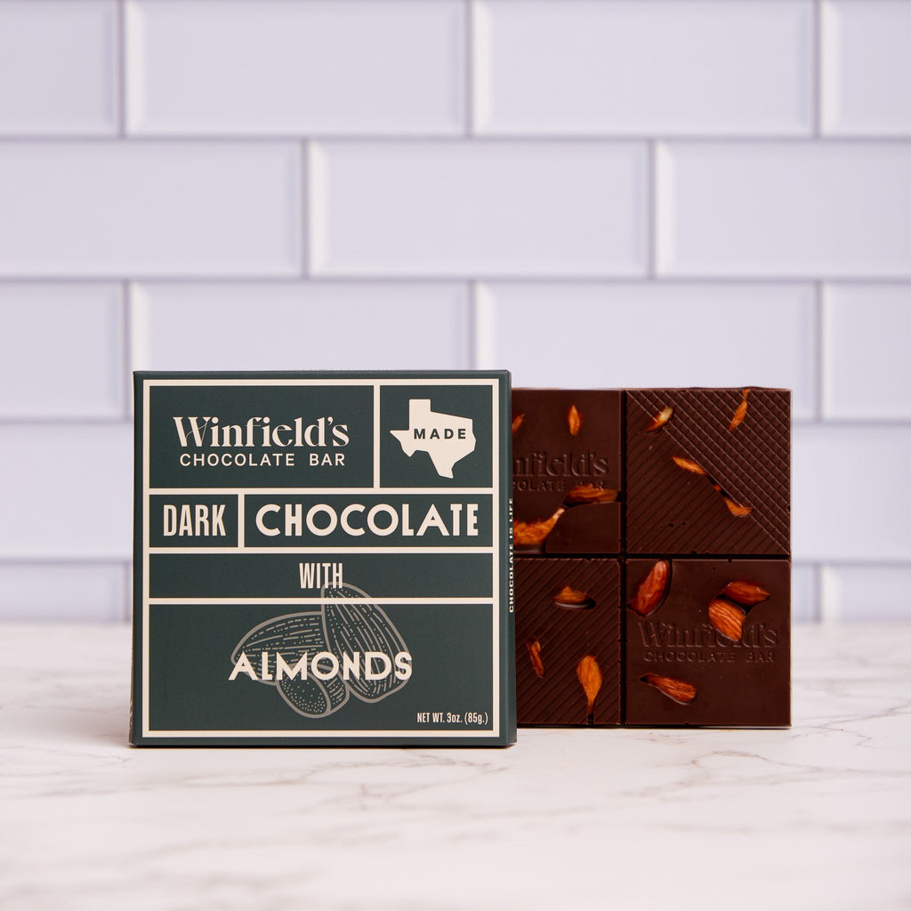 Winfield's Dark Chocolate with Almonds bar in its dark green wrapper beside the unwrapped almond-studded bar