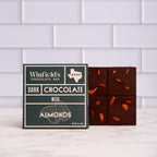 Winfield's Dark Chocolate with Almonds bar in its dark green wrapper beside the unwrapped almond-studded bar