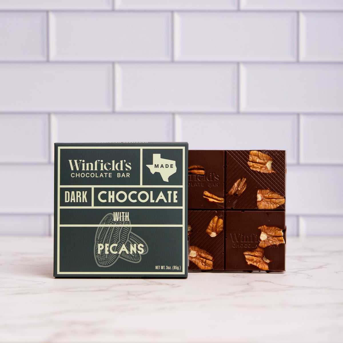 Winfield's Dark Chocolate with Pecans bar in its dark wrapper beside the unwrapped pecan-studded bar