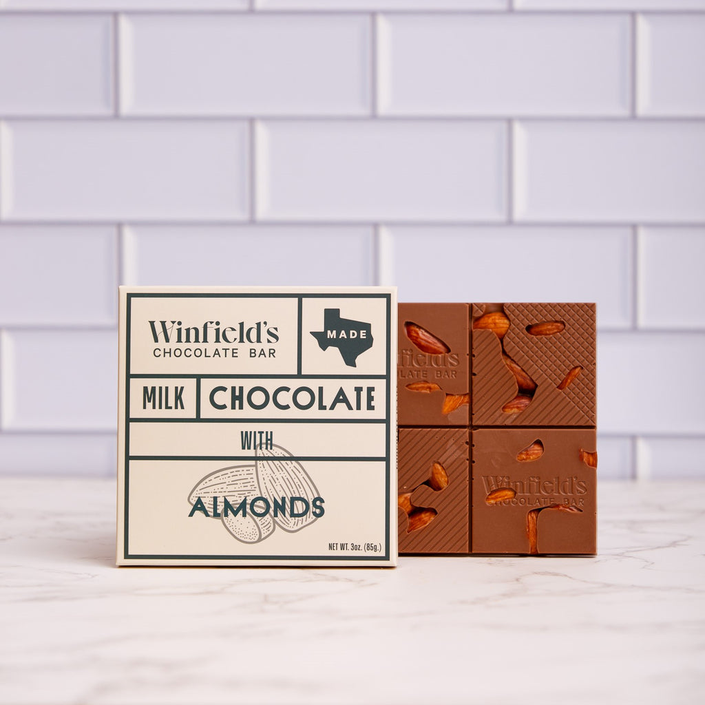Winfield's Milk Chocolate with Almonds bar in its cream wrapper beside the unwrapped almond-studded bar