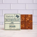 Winfield's Milk Chocolate with Pecans bar in its cream wrapper beside the unwrapped pecan-studded bar