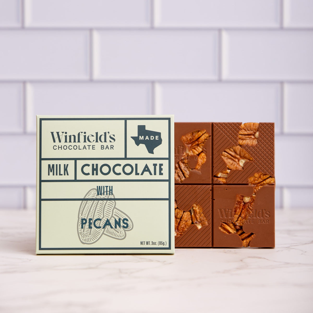 Winfield's Milk Chocolate with Pecans bar in its cream wrapper beside the unwrapped pecan-studded bar