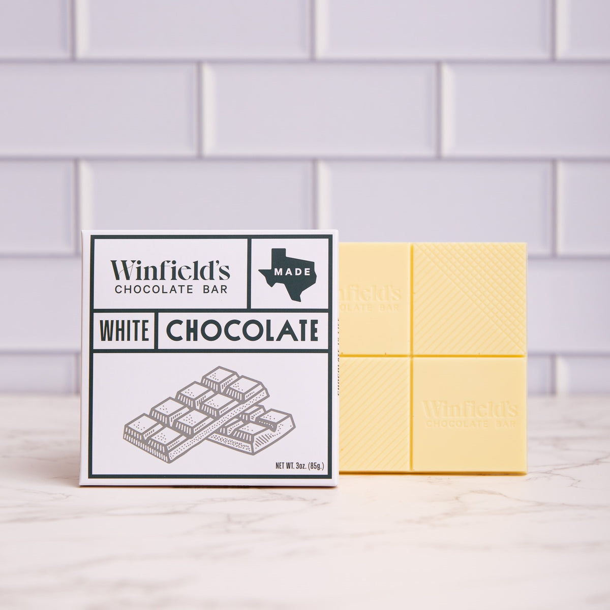 Winfield's solid White Chocolate bar in its white wrapper beside the unwrapped bar