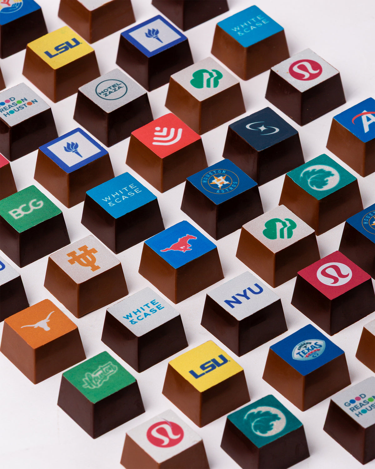 A close grid of Winfield's chocolate squares, each printed with a different university or corporate logo