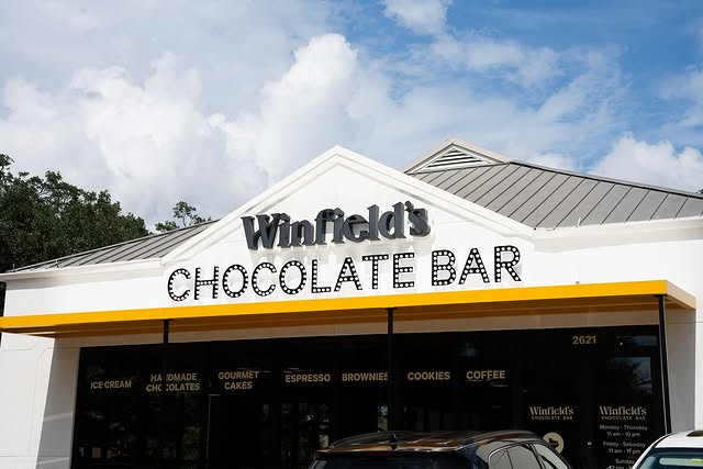 The Winfield's Chocolate Bar storefront at the Galleria, its yellow awning and shop sign under a blue sky