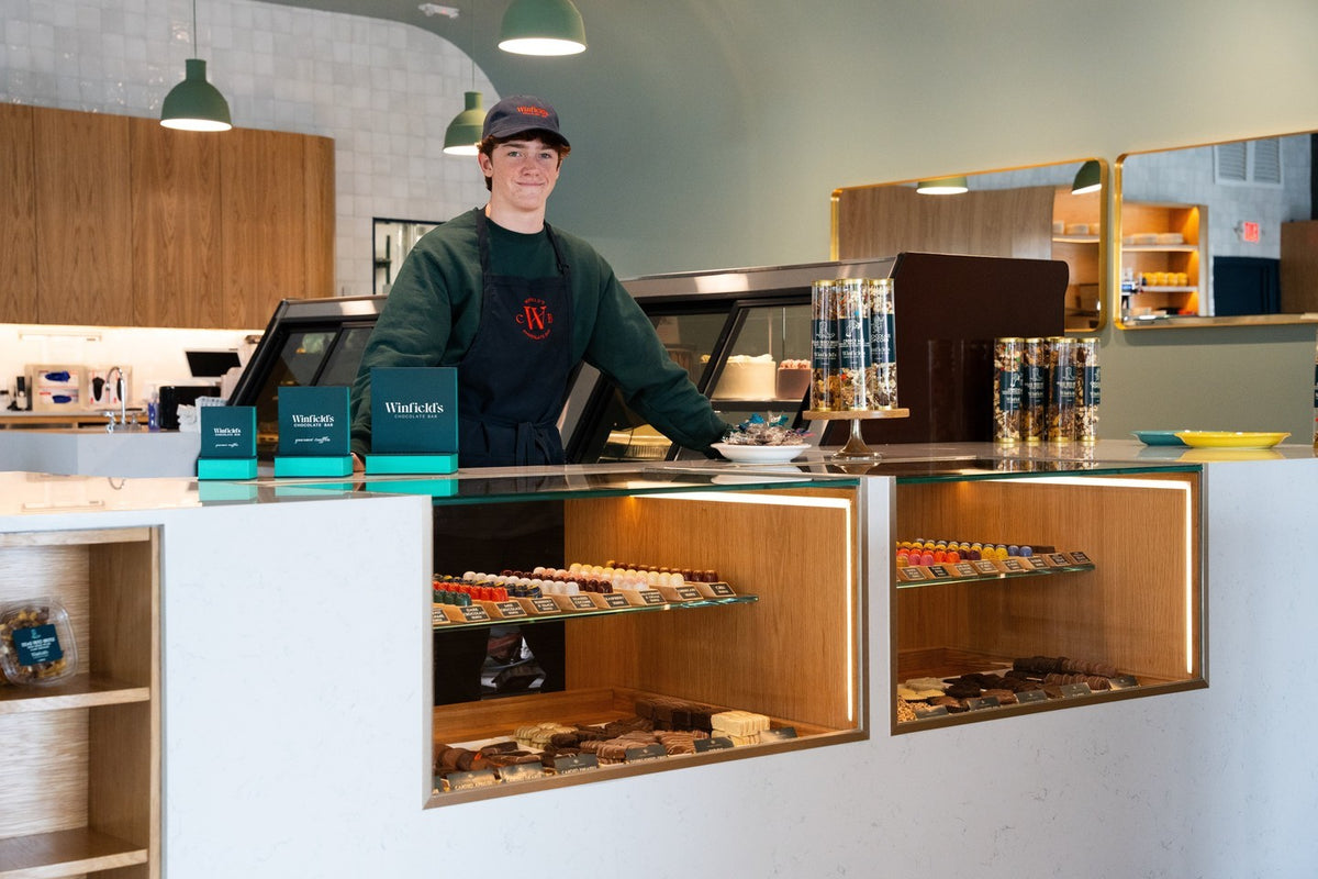 A Winfield's team member behind the chocolate counter in one of the Houston shops, trays of chocolates in the case