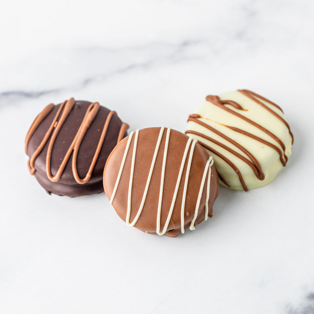 Three Winfield's chocolate-covered Oreos in dark, milk and white chocolate on marble