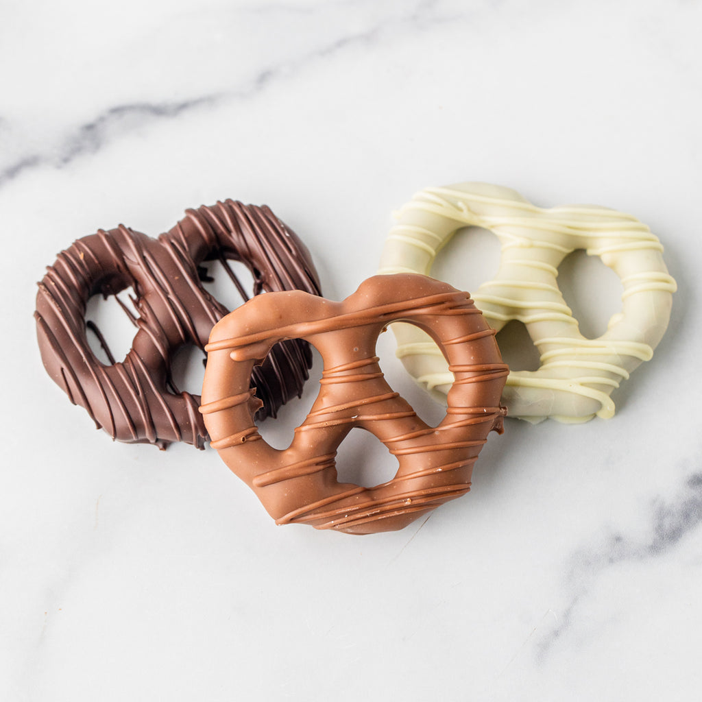 Three Winfield's chocolate-dipped pretzel twists in dark, milk and white chocolate on marble