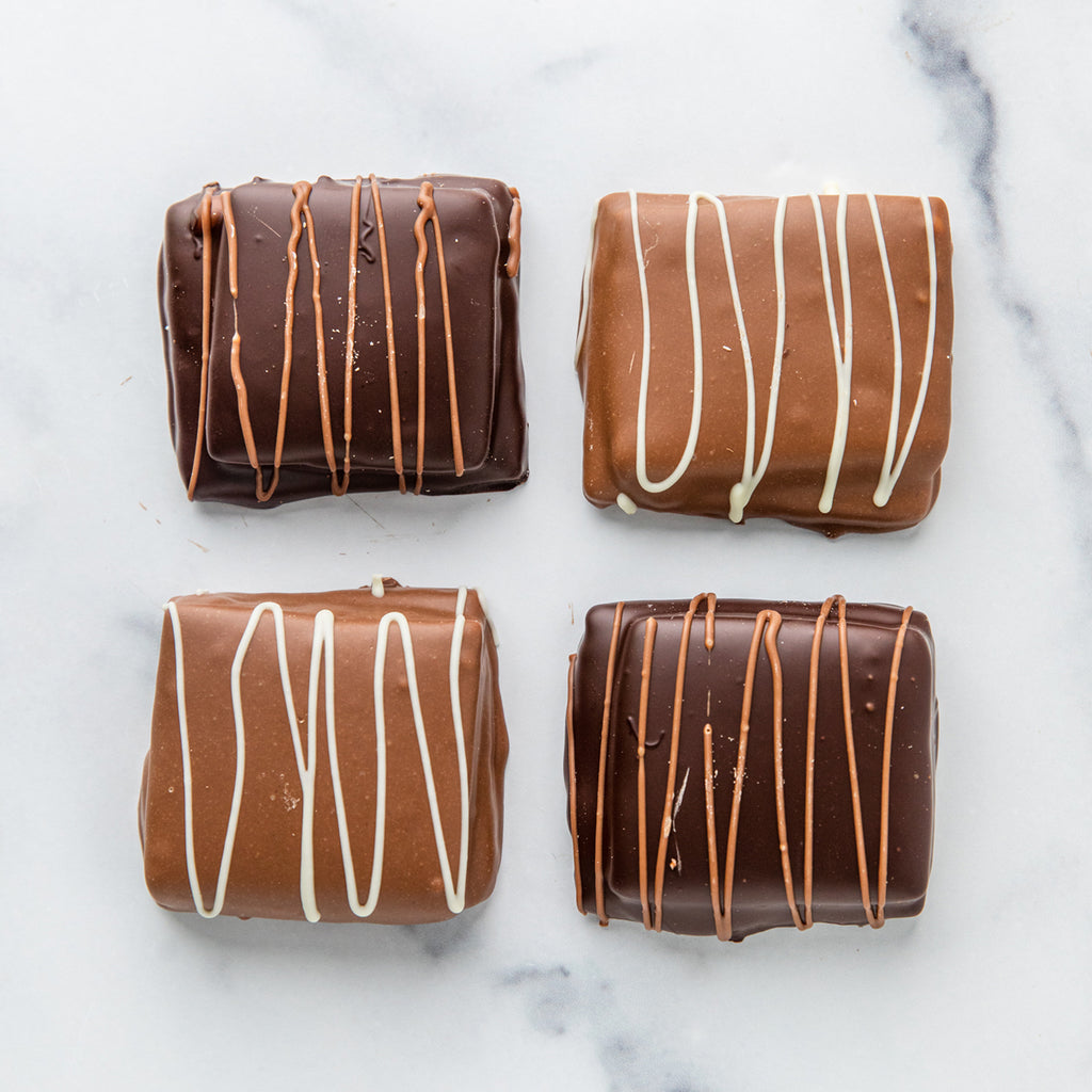 Four Winfield's chocolate-dipped s'mores with contrasting drizzle, on marble
