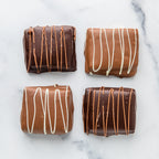 Four Winfield's chocolate-dipped s'mores with contrasting drizzle, on marble